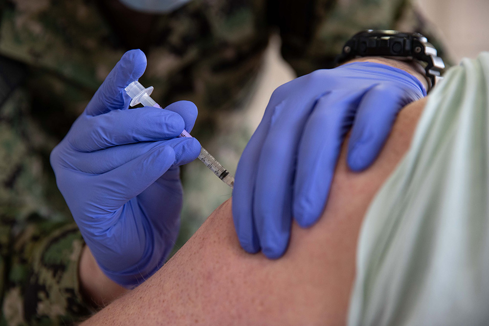Navy Petty Officer 3rd Class Joseph Casassa, assigned to USS Gerald R. Ford, administers a COVID-19 vaccine at the McCormick Gym at Naval Station Norfolk, Va., April 8, 2021. The Defense Logistics Agency has been packing and distributing COVID-19 vaccines to Defense Department employees and families outside the continental United States and to deployed sailors in the U.S. Navy fleet. © Navy Seaman Jackson Adkins