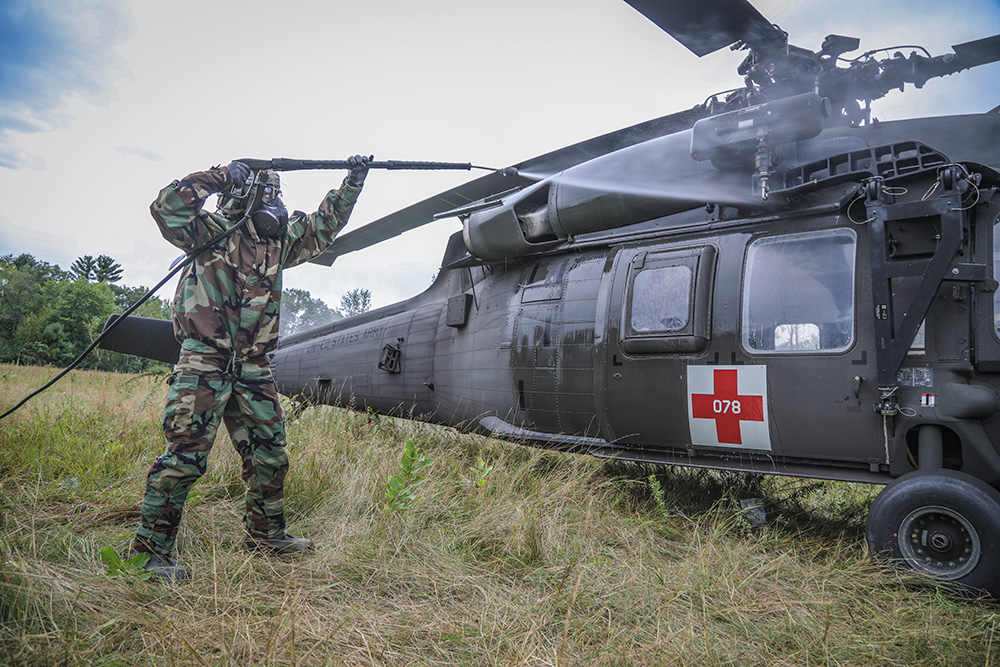 A soldier assigned to the 308th Chemical Company, 450th Chemical Battalion, 209th Regional Support Group, 76th Operational Response Command sprays water on a "contaminated" Black Hawk helicopter during a decontamination operation at Fort McCoy, Wis., Aug. 20, 2019. © Army Sgt. 1st Class Brent C. Powell