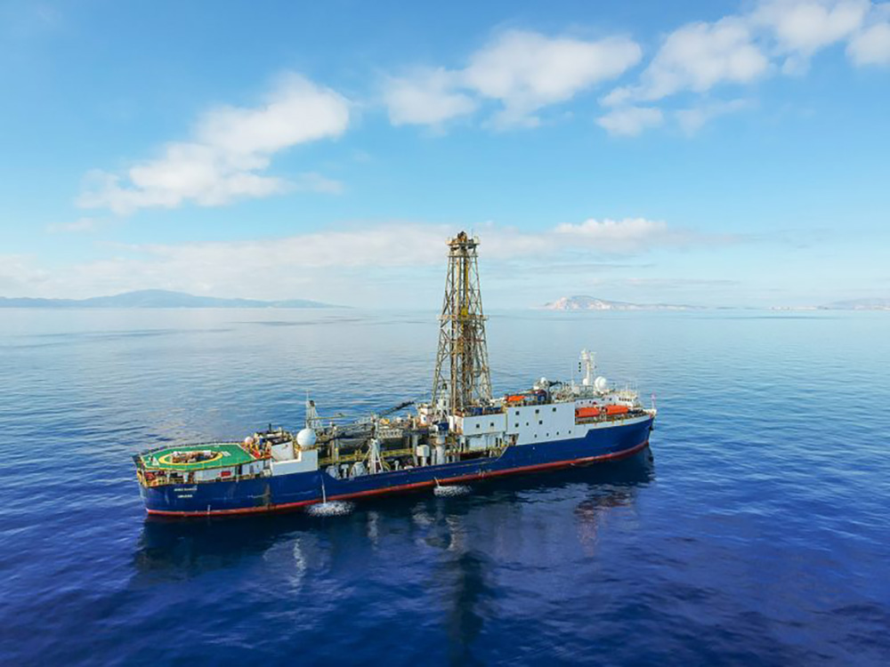 The scientific drilling ship Joides Resolution near the Greek island of Santorini in 2023. Aboard was mission scientist Adam Woodhouse, a postdoctoral fellow at the University of Texas Institute for Geophysics. His studies of microfossils gathered on previous missions have revealed how the climate affects global plankton populations. © Thomas Ronge