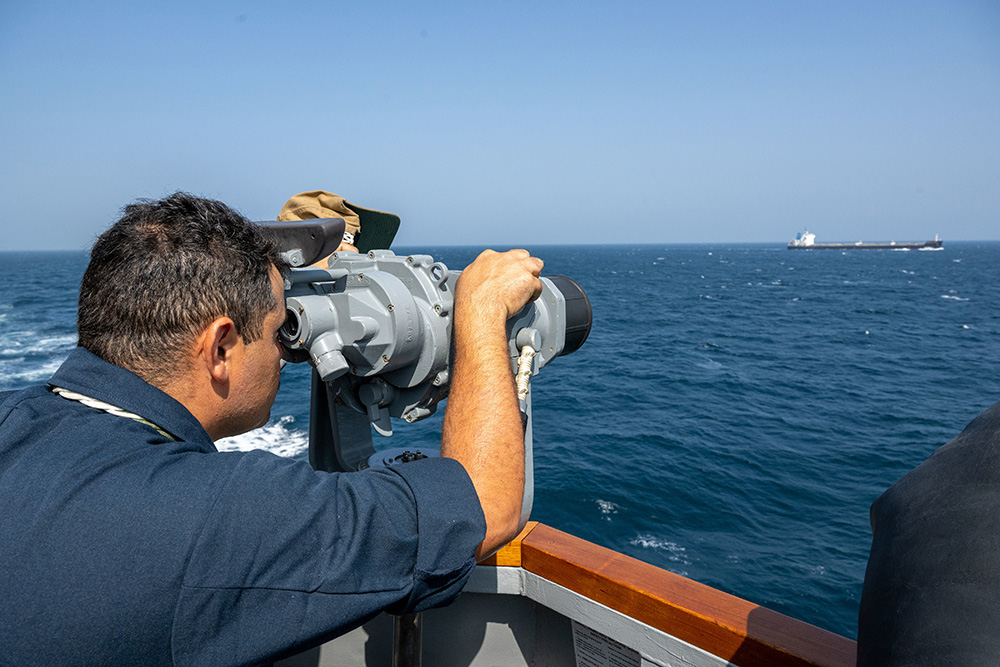 Navy Petty Officer 2nd Class Ahmed Elharoun looks through high powered binoculars at a passing oil tanker aboard the USS Mason while operating in support of Operation Prosperity Guardian in the Red Sea, Dec. 24, 2023. © Navy Petty Officer 1st Class Chris Krucke