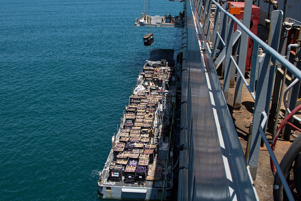 Soldiers use a crane to load humanitarian aid for civilians in Gaza. These soldiers are supporting the construction of the Joint Logistics Over-the-Shore system off the shore of Gaza. © Army Staff Sgt. Malcolm Cohens-Ashley