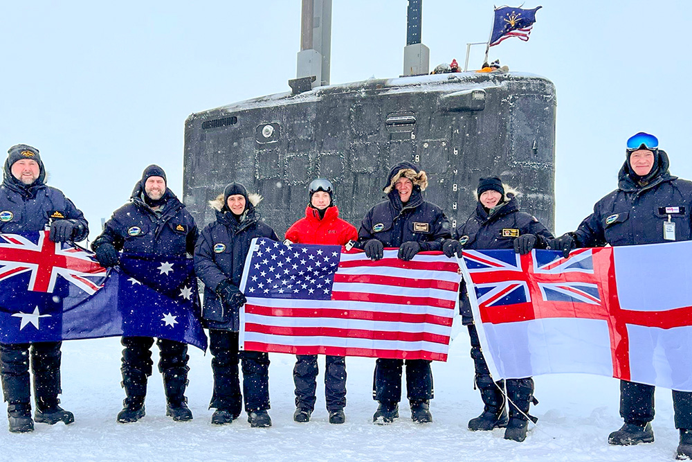 Navy personnel from the U.S., U.K. and Australia display flags outside of the USS Indiana while the submarine is surfaced in the Beaufort Sea, Arctic Circle during Operation Ice Camp, March 13, 2024. © Navy Lt. Sarah Niles