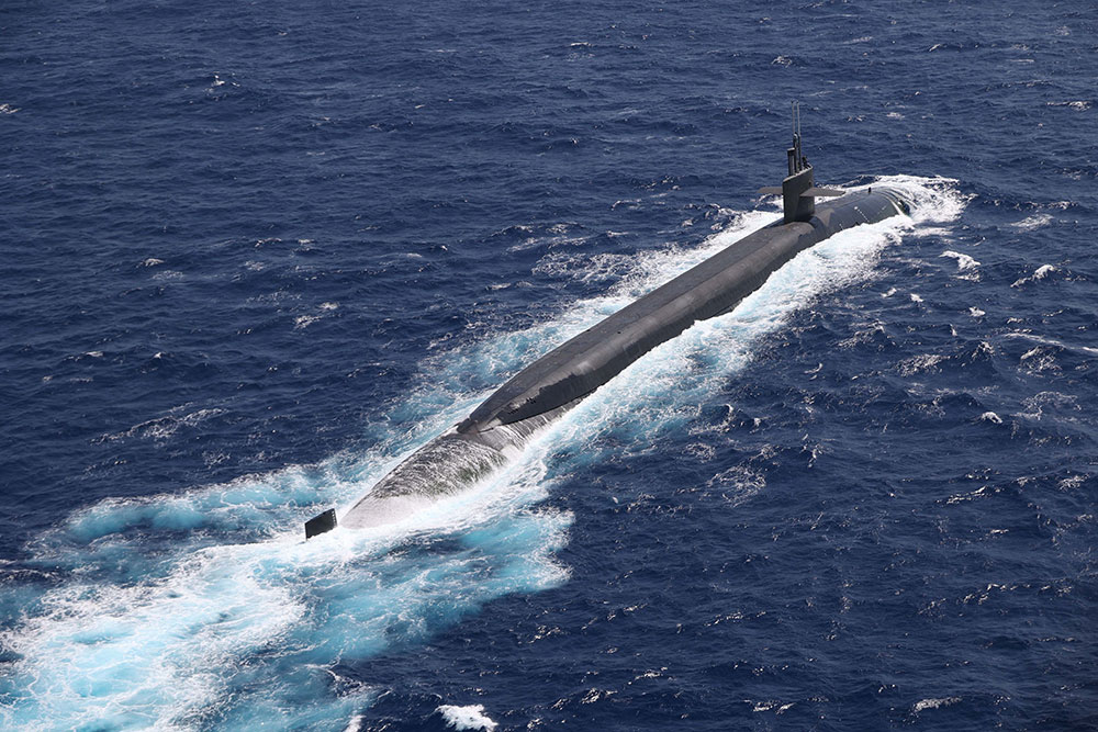 The ballistic missile submarine USS Maine surfaces to receive a vertical replenishment in the Philippine Sea, May 9, 2023. Vertical replenishments enable vessels to quickly receive critical resources without disrupting maritime security operations while underway. © Marine Corps Lance Cpl. Emily Weiss