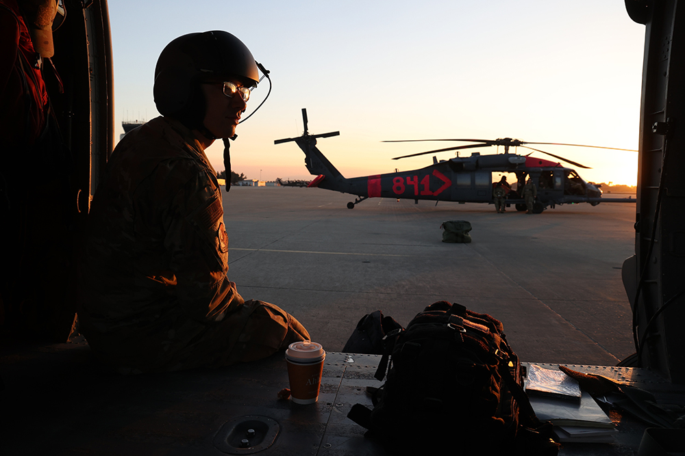 Air Force Airman 1st Class Alessandro Panighetti, an HH-60G Pave Hawk helicopter crew chief with the California Air National Guard, watches the sunrise on the ramp at Los Alamitos Army Airfield on Joint Forces Training Base, Los Alamitos, Calif., before traveling with the aircrew on a repositioning flight to a CAL FIRE helitack base, Jan. 11, 2025. © Air Force Staff Sgt. Crystal Housman