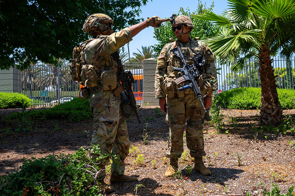 Army Spc. Joel Varughese and Capt. Nelson Laracuente survey the perimeter of an FBI building in Los Angeles, June 10, 2025. © Army Pfc. Joshua Fish