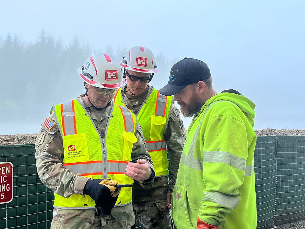 Army Brig. Gen. Joseph C. "Clete" Goetz, commanding general of the U.S. Army Corps of Engineers – Pacific Ocean Division, and Command Sgt. Maj. Zachary Plummer, senior enlisted advisor of the U.S. Army Corps of Engineers – Pacific Ocean Division, discuss street flood mitigation and response efforts with a city employee in Juneau, Alaska, Aug. 13, 2025. Goetz and Plummer traveled from a command center in Hawaii to Juneau to engage with the community and closely monitor the effectiveness of temporary flood protection barriers. © Nahaku McFadden, U.S. Army Corps of Engineers