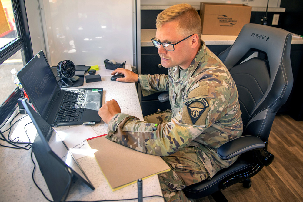 Army Sgt. Brandon Ashbrook, a human resources specialist assigned to the West Virginia Army National Guard, performs administrative tasks inside an office trailer at Logistics Support Area Lincoln at Joint Base Anacostia-Bolling, Washington, Aug. 27, 2025. © Army Spc. Carrol Walter Hughes IV